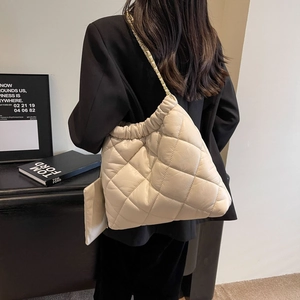 Detail of a cream quilted tote bag with gold chain strap and matching small pouch