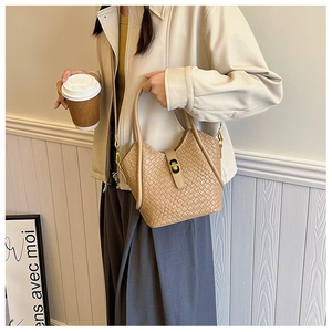 Vue détaillée de la texture en cuir tressé et du fermoir doré du sac seau beige