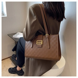 Detailed view of brown tote bag with checkered embossing and elegant golden buckle closure