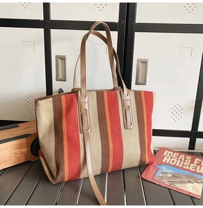 Large striped canvas tote bag with brown leather straps in a cozy home setting