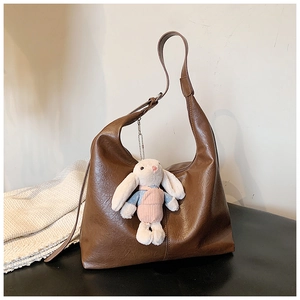 Detail of dark brown leather tote bag texture with a cute plush bunny charm accessory