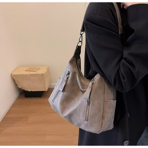 Close-up of a large grey vintage leather tote bag featuring functional side pockets and zippers