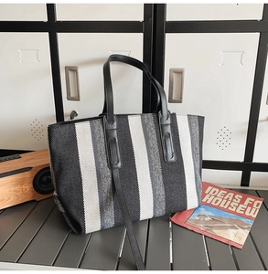 Close-up of striped canvas tote bag with black leather handles and shoulder strap