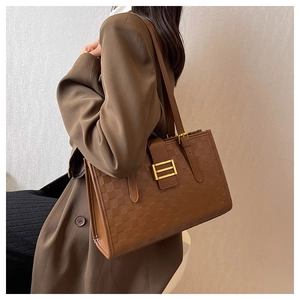 Detail of vintage brown tote bag with checkerboard embossing and gold metal buckle