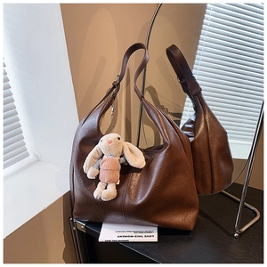 Detail of dark brown tote bag with retro leather texture and a cute rabbit charm