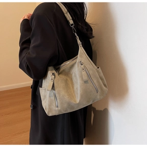 Detail view of large sage green tote bag with multiple metal zipper pockets and wide strap
