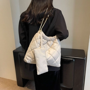 Close-up of white quilted tote bag with chain strap and matching small zipper pouch