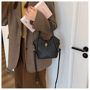 Détail du sac seau en cuir tressé noir avec fermoir rotatif doré et bandoulière amovible