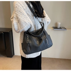 Detail of black faux leather tote bag with metallic zipper and adjustable shoulder strap