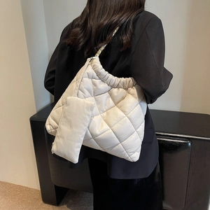 Close-up of beige quilted tote bag with matching mini pouch and metal chain detail
