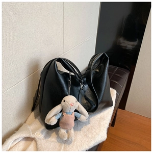 Detail view of large black PU leather tote bag with a cute plush rabbit charm
