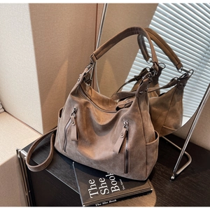 Detail view showing textured brown suede hobo bag with zip pockets and side compartments
