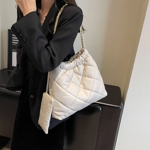 Detail of quilted tote bag featuring drawstring closure and gold chain strap accent