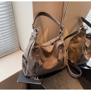 Close-up of brown suede tote bag with dual vertical zippers and vintage metal details