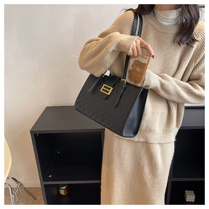 Detail of black checkered tote bag with gold magnetic buckle and long shoulder strap