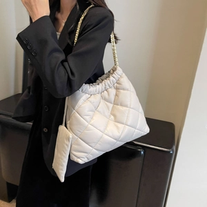 Detail of white quilted tote bag with gold chain strap and mini coin purse attachment