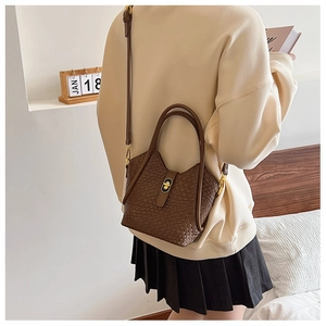 Détail du sac seau marron à texture tissée avec fermoir doré et bandoulière