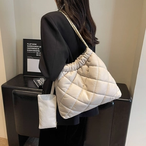 Detail view of cream quilted tote bag with chain strap and matching small zipper pouch