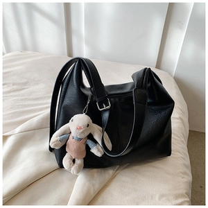 Detail of black litchi grain tote bag with adjustable silver buckle and rabbit plush charm