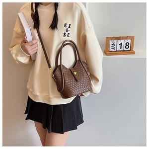 Détail du sac seau marron tressé avec fermoir doré et bandoulière amovible élégante
