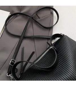 Detail of black textured leather tote with adjustable shoulder strap and silver zipper