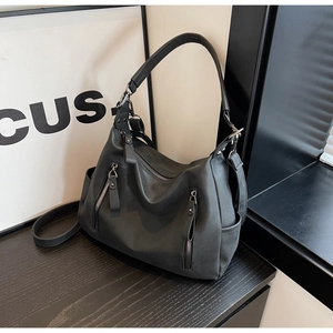 Detail of dark grey tote bag featuring vertical zippers and adjustable shoulder straps