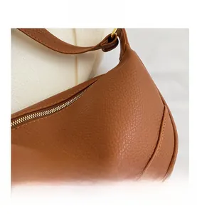 Close-up of caramel leather shoulder bag showing lychee grain texture and gold zipper