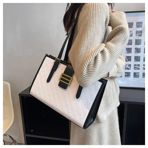 Detailed view of large tote bag with black and white grid texture and gold square buckle