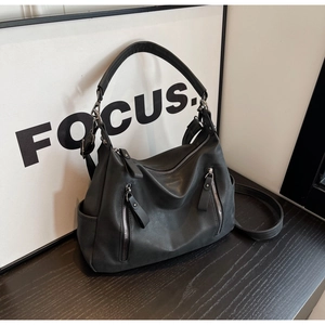 Detail view of black matte leather tote bag with functional zippers and crossbody strap