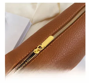 Detail of smooth gold zipper on brown lychee texture leather shoulder bag