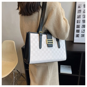 Detail view of large checkered tote bag with gold buckle hardware on a female model