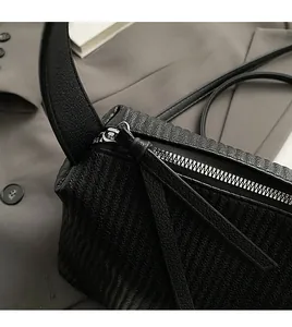Close-up of smooth silver metal zipper and geometric leather texture on black tote bag