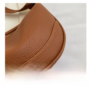 Detailed macro view of brown pebbled leather texture with yellow stitching and gold zipper