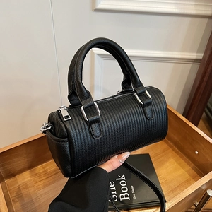 Minimalist black quilted barrel bag with silver hardware and detachable strap in a setup
