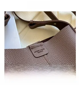 Close-up of brown litchi grain leather texture and handle stitching on a bucket bag