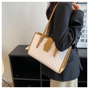 Detail of white checkered tote bag with brown leather handles and gold buckle on shoulder