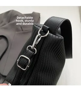 Detail of sturdy silver detachable metal hooks and litchi texture on black leather bag
