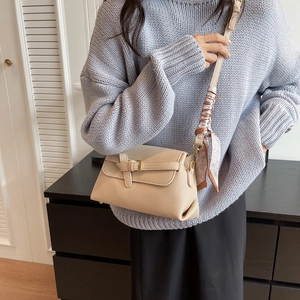 Beige textured crossbody bag with gold buckle and heart silk scarf on the strap