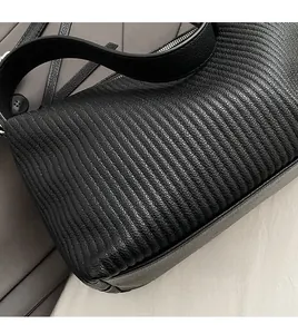 Close-up of black vertical pleat texture and wide strap on the luxury tote bag