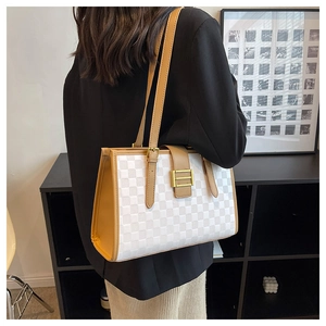 Detail view of stylish checkered tote bag with golden metal buckle and leather strap