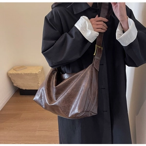 Detail van bruine hobo-tas met verstelbare gouden gesp op de schouderband van de tas