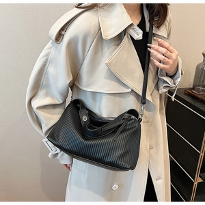 Detail of vintage black textured leather tote bag worn with a stylish trench coat