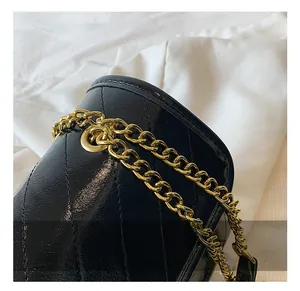 Macro detail of high-quality gold metal grommets and woven leather chain on a black quilted bag