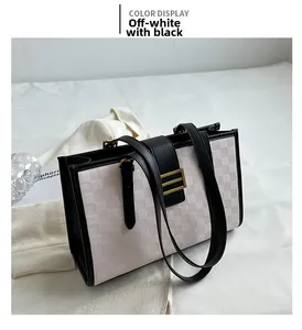 Detailed close-up of beige waffle texture tote bag with black leather trim and gold buckle
