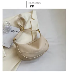 Detail of creamy white crescent shoulder bag with lychee grain texture and gold hardware