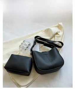 Detail view of black lychee grain bucket bag and matching pouch on soft textured fabric
