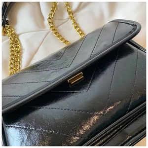 Detailed macro of black chevron quilted leather with golden square lock and chain