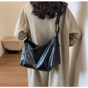 Detailweergave van de zwarte grote hobo-tas op de schouder met goudkleurige gesp