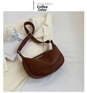 Detail of coffee crescent shoulder bag with pebbled leather texture and gold hardware
