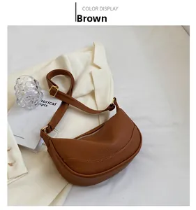 Detailed view of a brown hobo shoulder bag with litchi grain texture and gold buckles